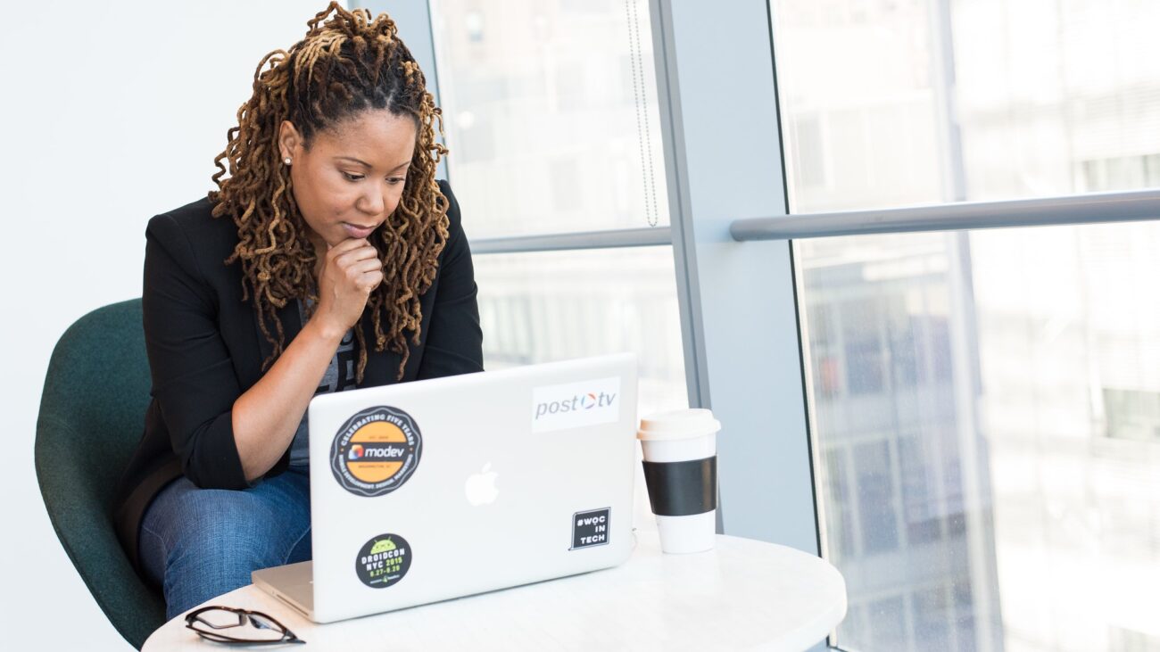 Black woman on MacBook with coffee