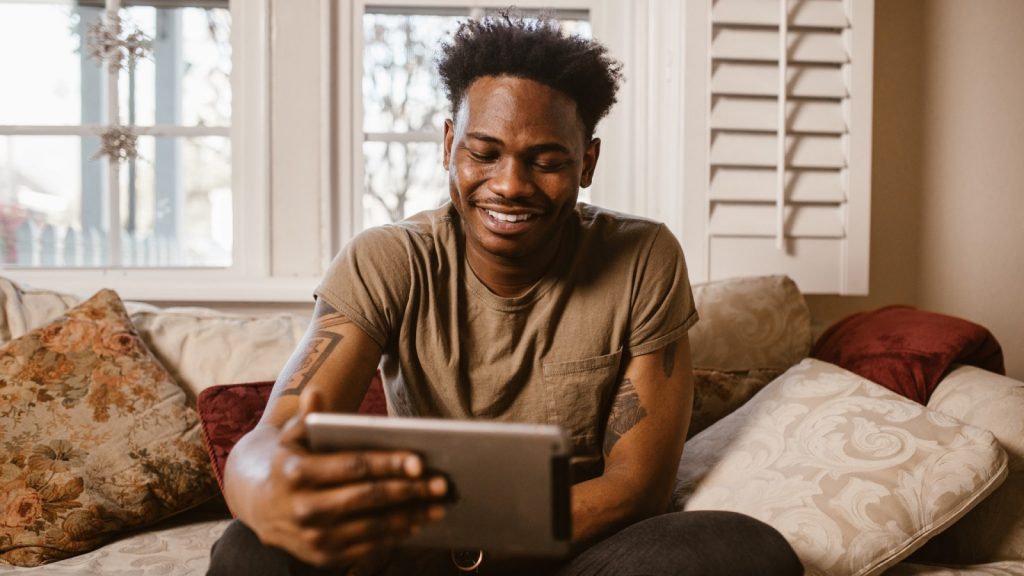 Black man smiling at something on an iPad