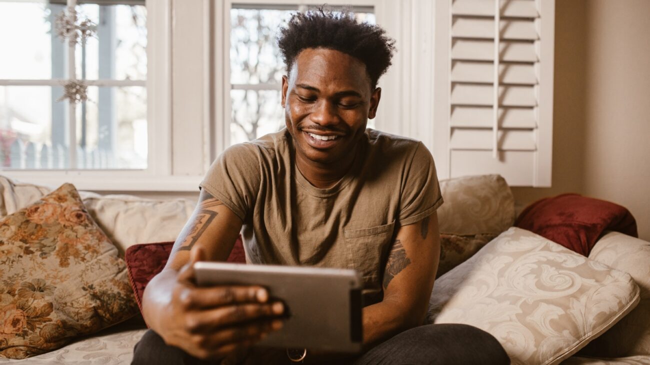 Black man smiling at something on an iPad