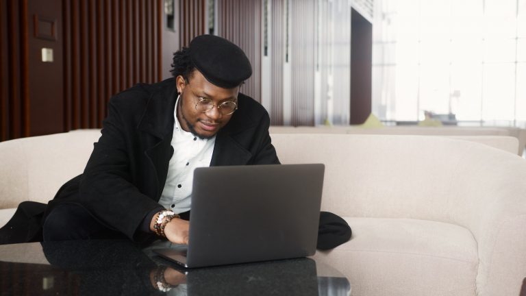 Black man with a hat at a laptop