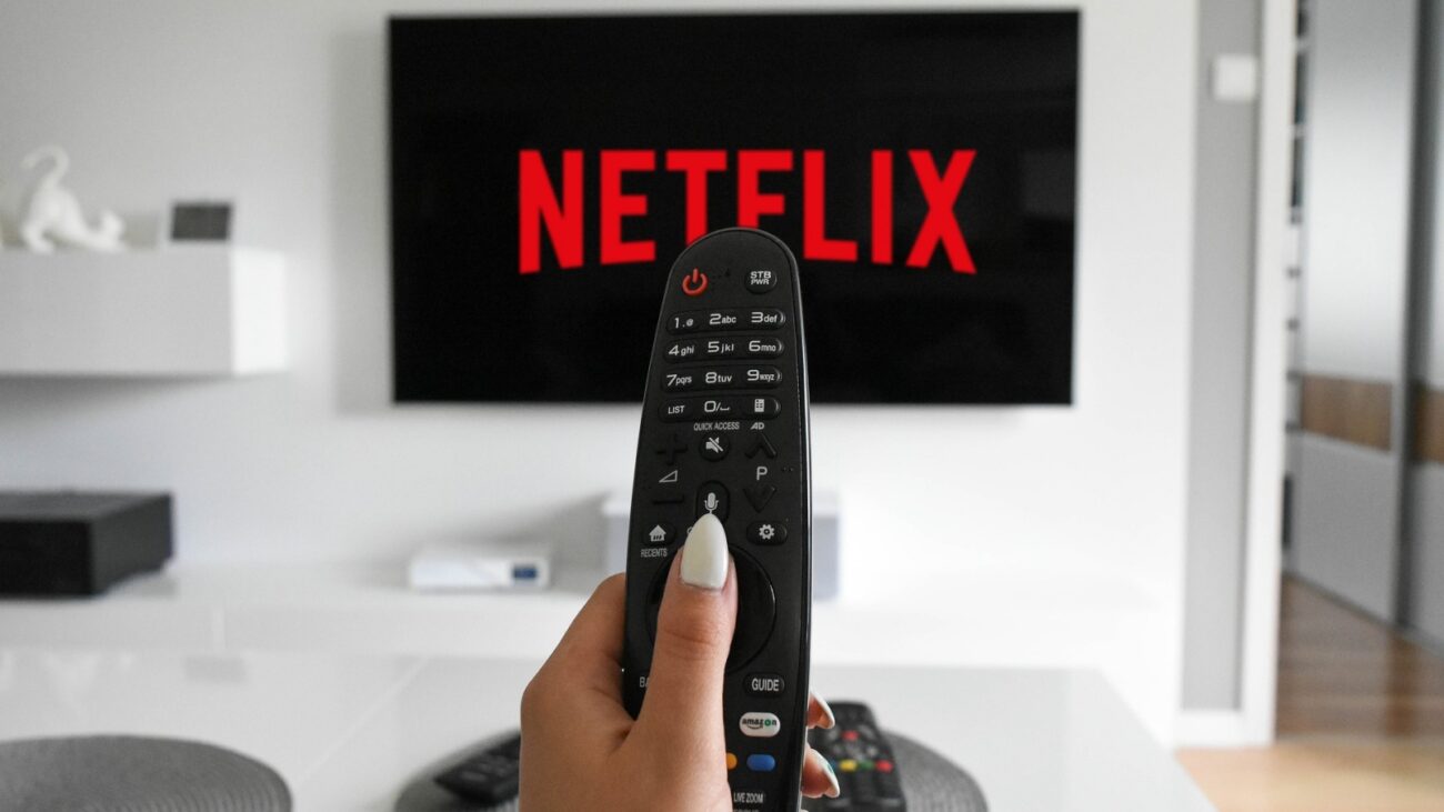 Woman holding a remote for a TV on Netflix