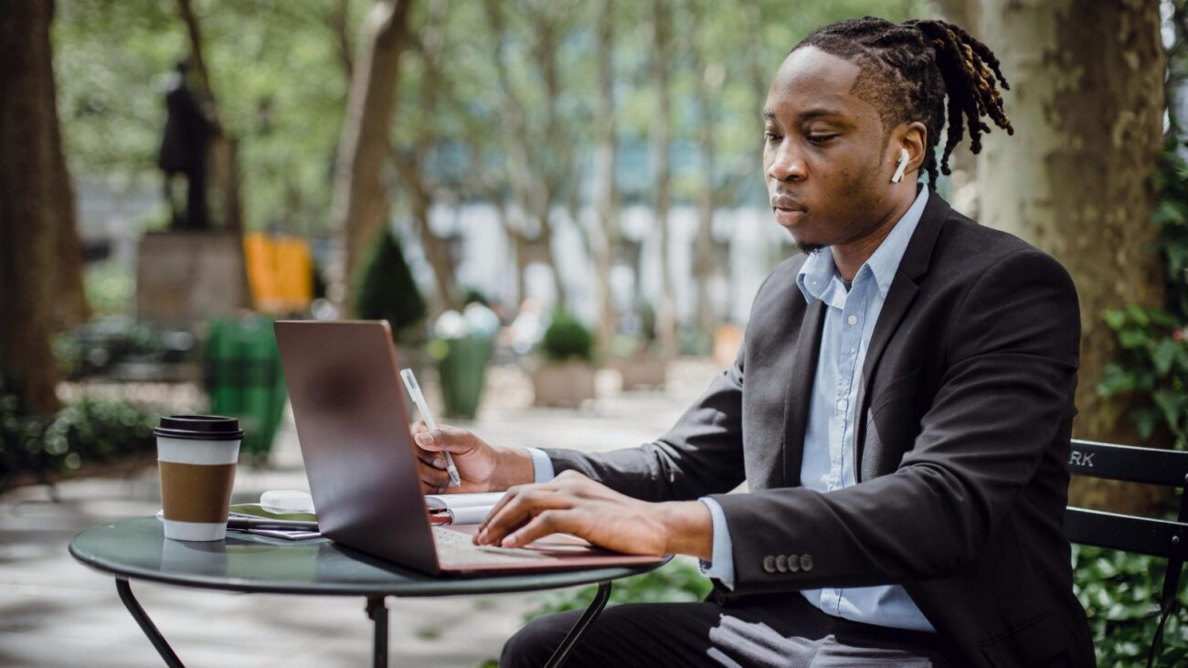 Black man on laptop with coffee nearby